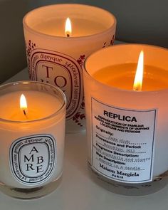 three candles sitting on top of a table next to each other with labels on them