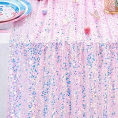 a table with pink and blue sequins on it, plates and napkins