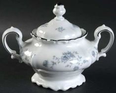 a white tea pot with blue flowers on it and a black border around the top