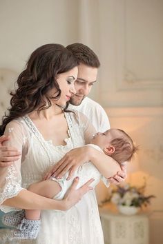 a man and woman holding a baby in their arms