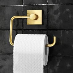 a gold toilet paper holder on a black tiled wall