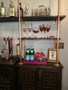 there is a shelf with glasses and bottles on top of it, along with other items