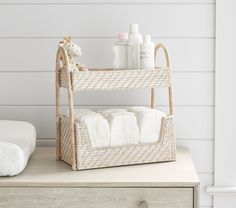 a wicker shelf with towels and soaps on it next to a white wall