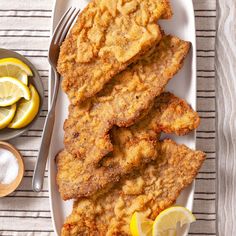 fried fish on a plate with lemon slices