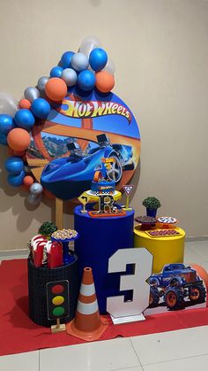 a birthday party with balloons and toys on the floor in front of a sign that says hot wheels