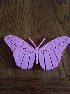 a pink butterfly shaped object sitting on top of a wooden table