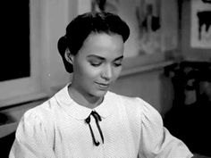 a woman sitting at a table with a plate of food in front of her and looking down