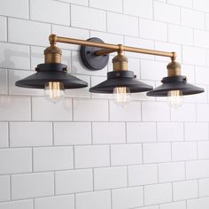 three lights are hanging from the side of a white brick wall in an industrial - style bathroom