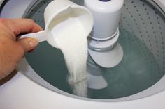 a person pouring sugar into a washing machine