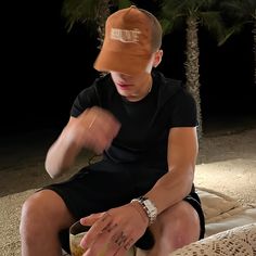 a young man sitting on top of a bed next to palm trees