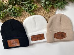 three beanies sitting next to each other on top of a white table with green leaves