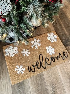 a welcome mat with snowflakes on it next to a christmas tree