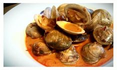 some clams are sitting on a plate with sauce