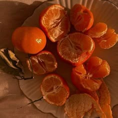 an orange cut in half sitting on top of a white plate next to dried leaves