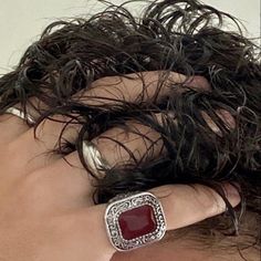 a close up of a person's hand with a ring on their finger and hair in the background