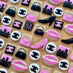 decorated cookies with pink and black designs on top of a wooden table in the shape of women's shoes