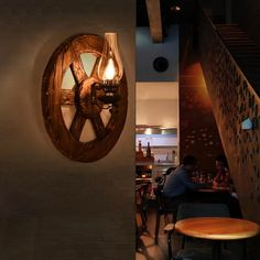 a man sitting at a table in front of a wall mounted wooden wheel on the wall