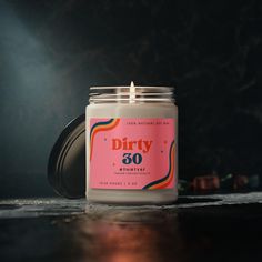 a white candle sitting on top of a table next to a canister filled with dirty