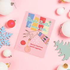 a pink christmas card surrounded by ornaments and snowflakes