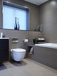 a white toilet sitting next to a bath tub in a bathroom under a large window