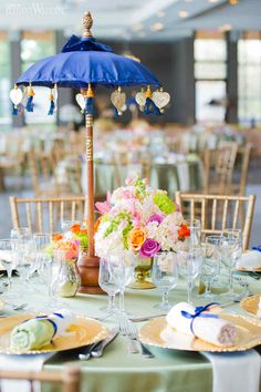 a table set up with plates, glasses and an umbrella in the middle of it