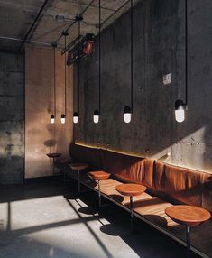 a row of benches sitting next to each other in front of a wall with lights on it