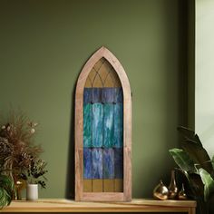 a stained glass window sitting on top of a mantle next to a potted plant