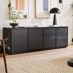 a living room with black furniture and art on the wall, including a large plant