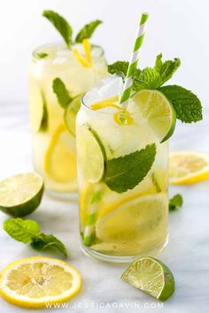 two glasses filled with lemonade, lime and mint