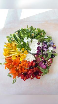 a bunch of different colored flowers arranged in a circle on top of a white surface