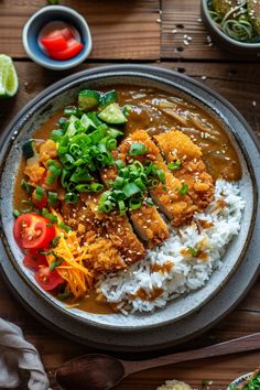 a bowl filled with rice, meat and veggies on top of a wooden table