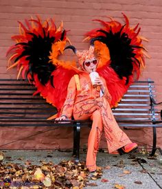 a woman sitting on top of a bench wearing an orange and black costume