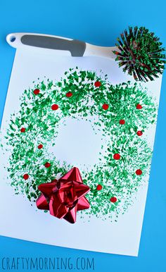 a paper christmas wreath on a cutting board with a red bow and pineconi