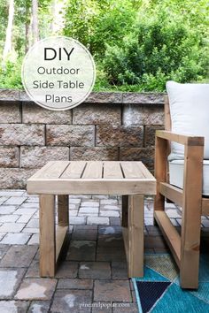 a wooden table sitting on top of a brick patio next to a white chair and blue rug