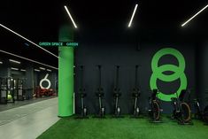 an indoor gym with exercise equipment and green space greens logo on the wall behind it