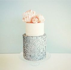 a three tiered cake decorated with flowers on a white tablecloth and blue background