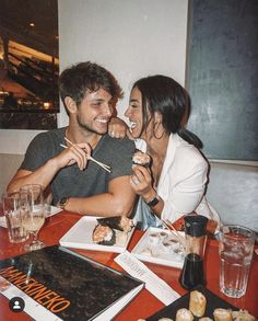 two people sitting at a table eating sushi