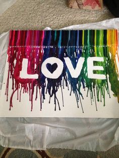 a piece of paper with the word love painted on it in white and rainbow colors