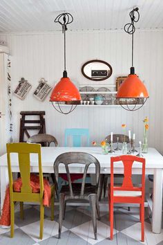 a dining room table with four chairs and two pendant lights hanging over the top of it