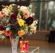 a vase filled with lots of flowers on top of a table next to a card