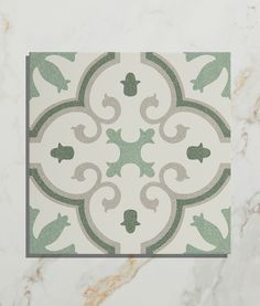 a tile with green and white designs on the wall in a room that has marble flooring