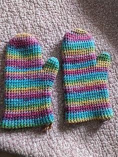 two crocheted mittens sitting on top of a blanket