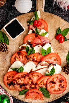 tomatoes and mozzarella on a wooden platter with pine cones, christmas decorations and candles