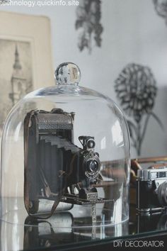 an old fashioned camera under a glass dome