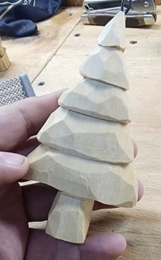 a hand holding a small wooden christmas tree