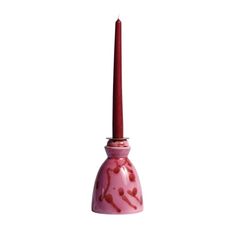 a pink candle holder with a single red candle in the middle and a white background