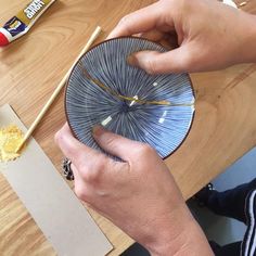 a person holding a blue plate on top of a wooden table with chopsticks