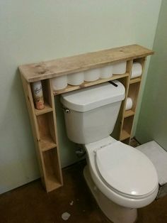 a white toilet sitting next to a wooden shelf