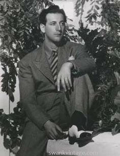 a man in a suit and tie sitting on a bench with his hand on the ground