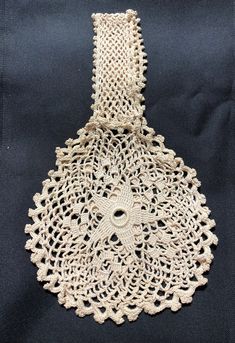 an old crocheted doily is displayed on a black cloth with white trim